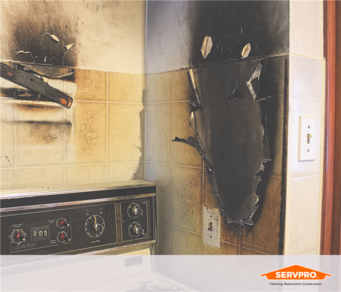 smoke damage to a kitchen above an old 80's looking stove, servpro logo in corner
